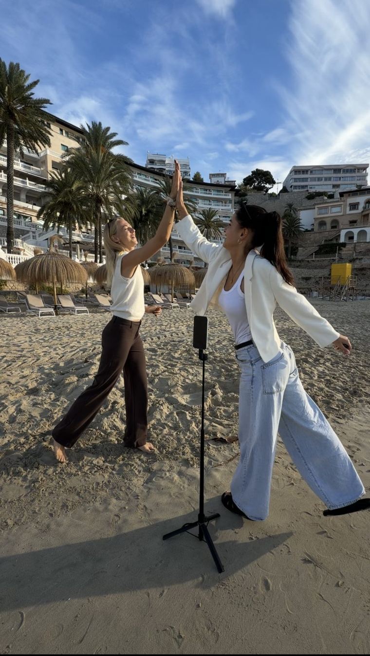Nancy und eine Kundin geben sich beim Content-Shooting am Strand auf Mallorca ein High Five